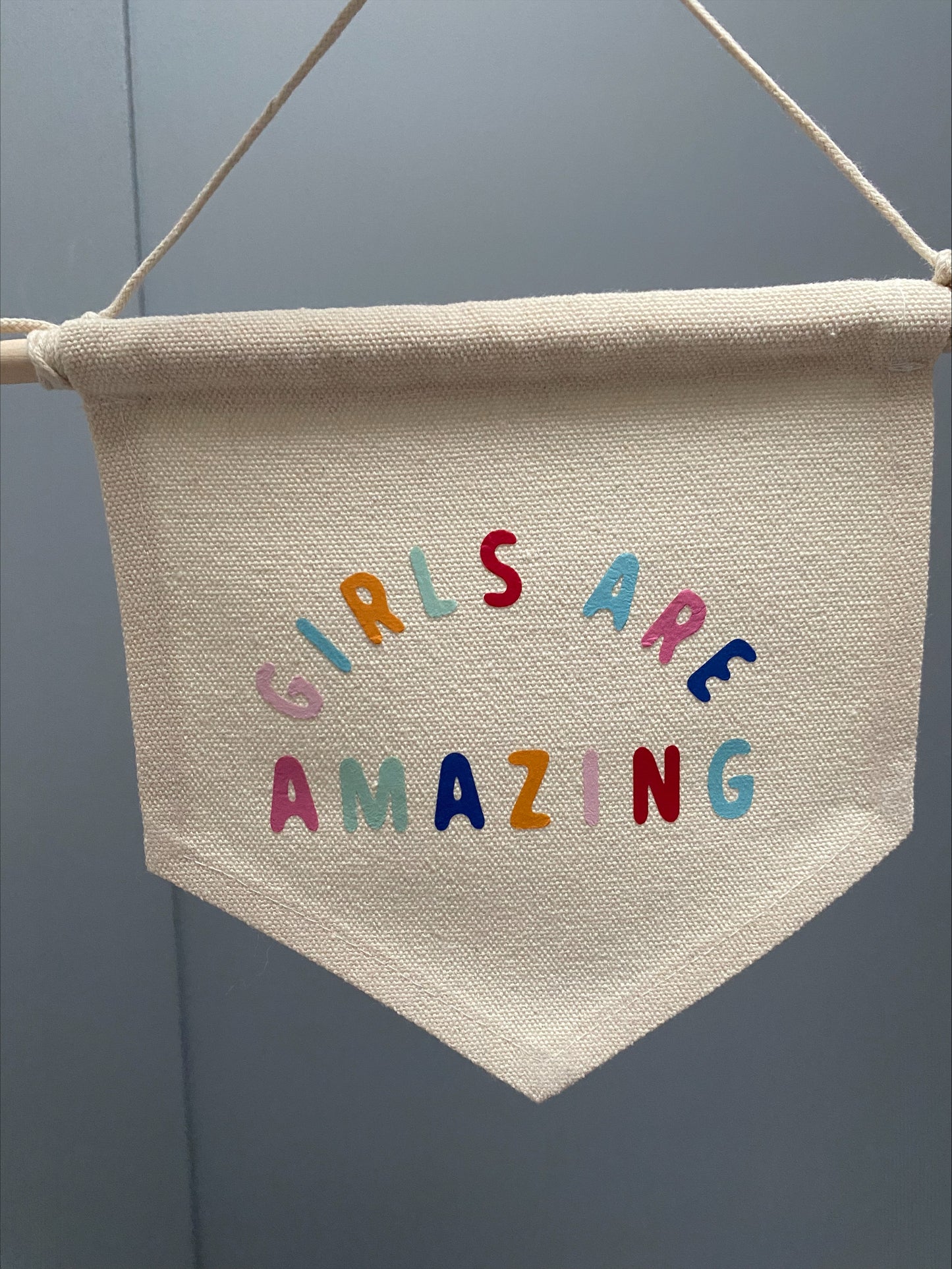 girls are amazing pennant flag, a beige background with multi coloured text